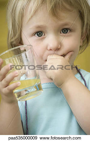 Stock Photograph of Toddler girl holding glass of juice, covering.