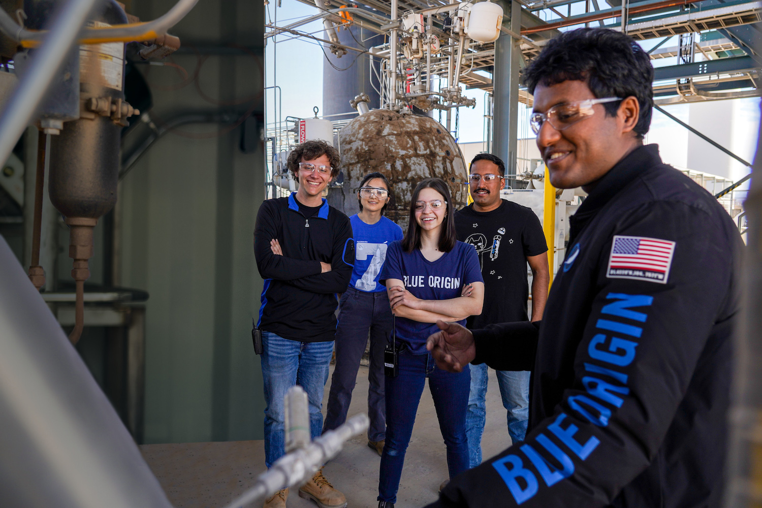 A group of interns wearing Blue Origin attire working in a rocket facility