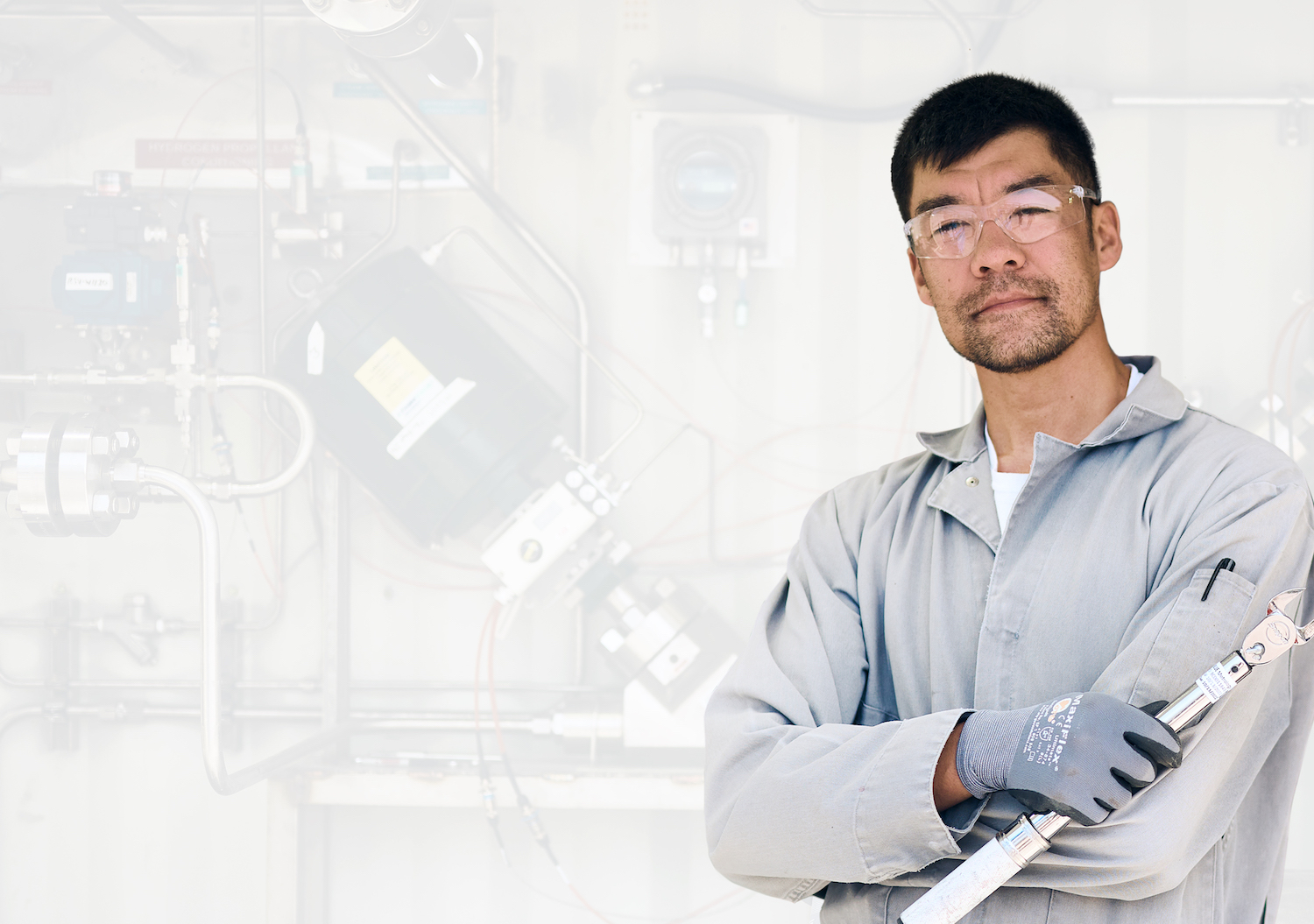 A man in a collared shirt holding a wrench with gloves