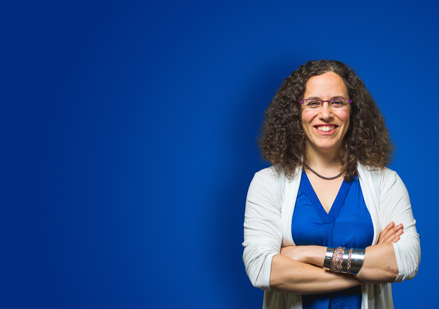 Smiling woman in business casual clothing with her arms crossed