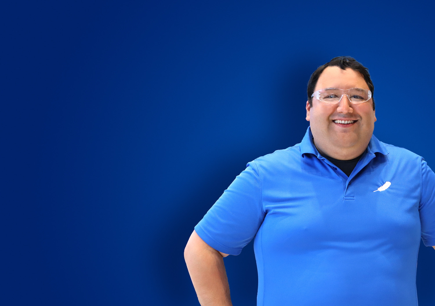 Smiling man with safety glasses and a Blue Origin polo