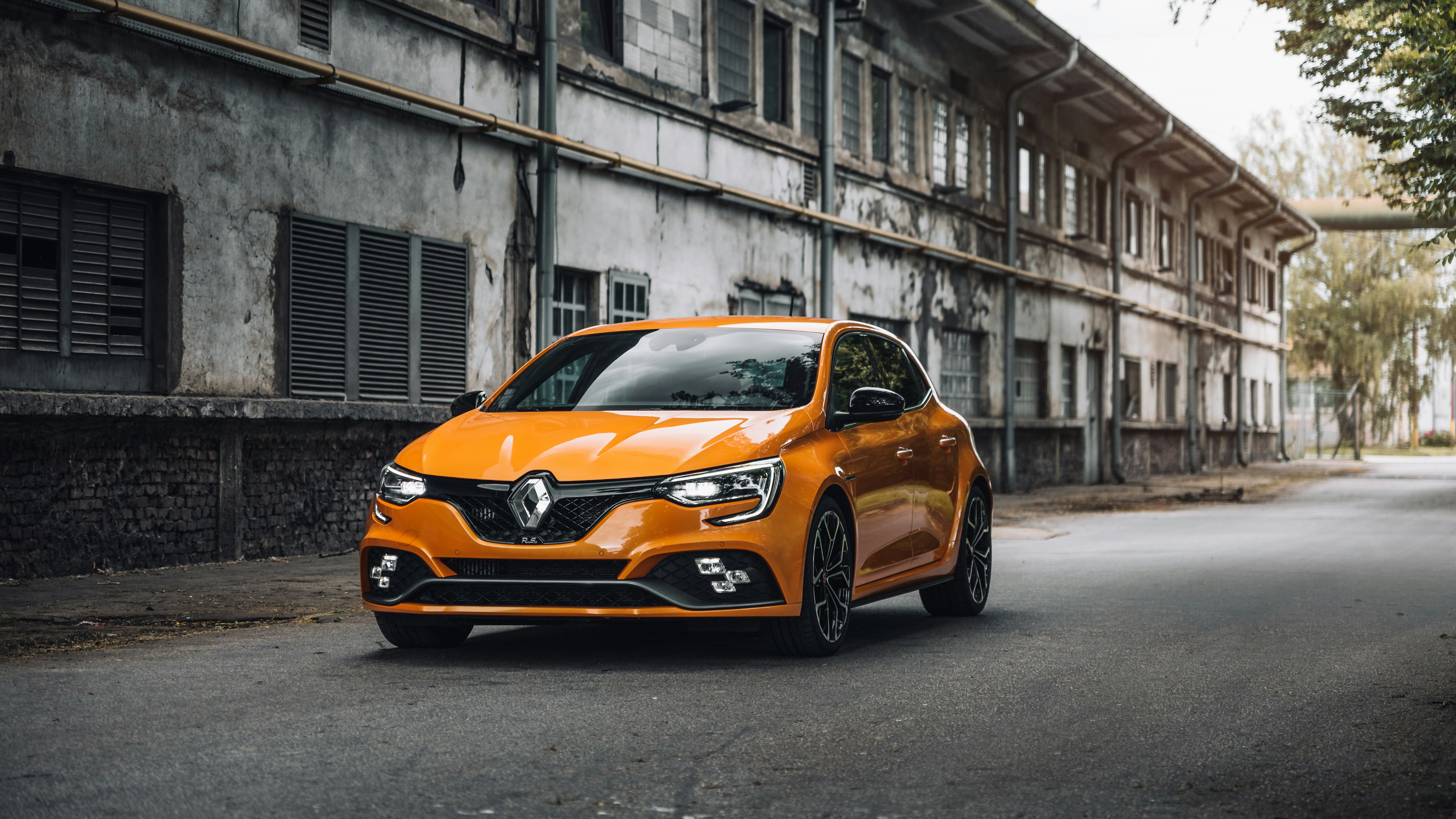 Image of an orange Renault car, on a street road