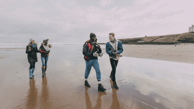 four friends walking and talking along the beach during winter