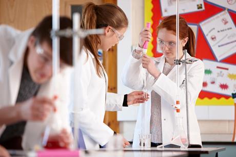 Students in a school lab using a burette filler to measure liquid for a titration