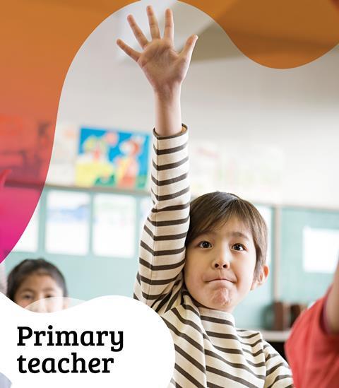 A primary school child raises their hand in a classroom