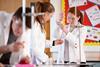 Students in a school lab using a burette filler to measure liquid for a titration