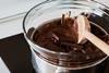 Chocolate melting in a glass bowl inside a metal saucepan on the stove