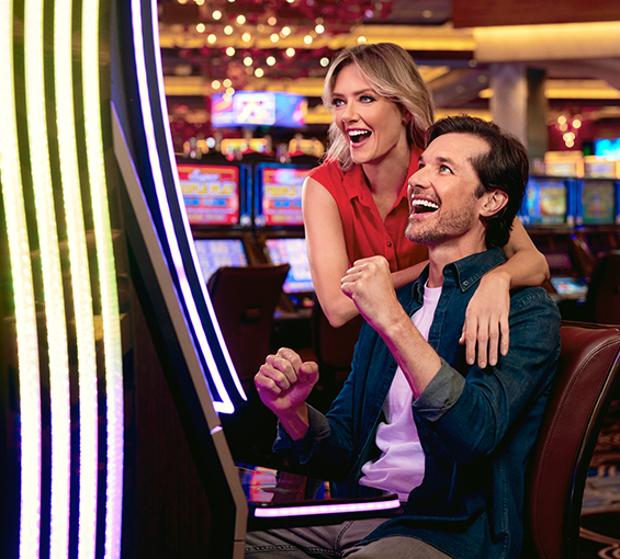Couple smiling and sitting at a slot machine having just won a jackpot at Graton Resort & Casino