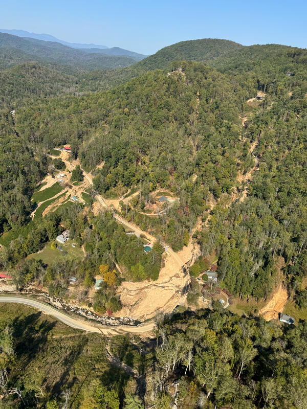 Aerial view of landslide amongst green trees in the mountains 