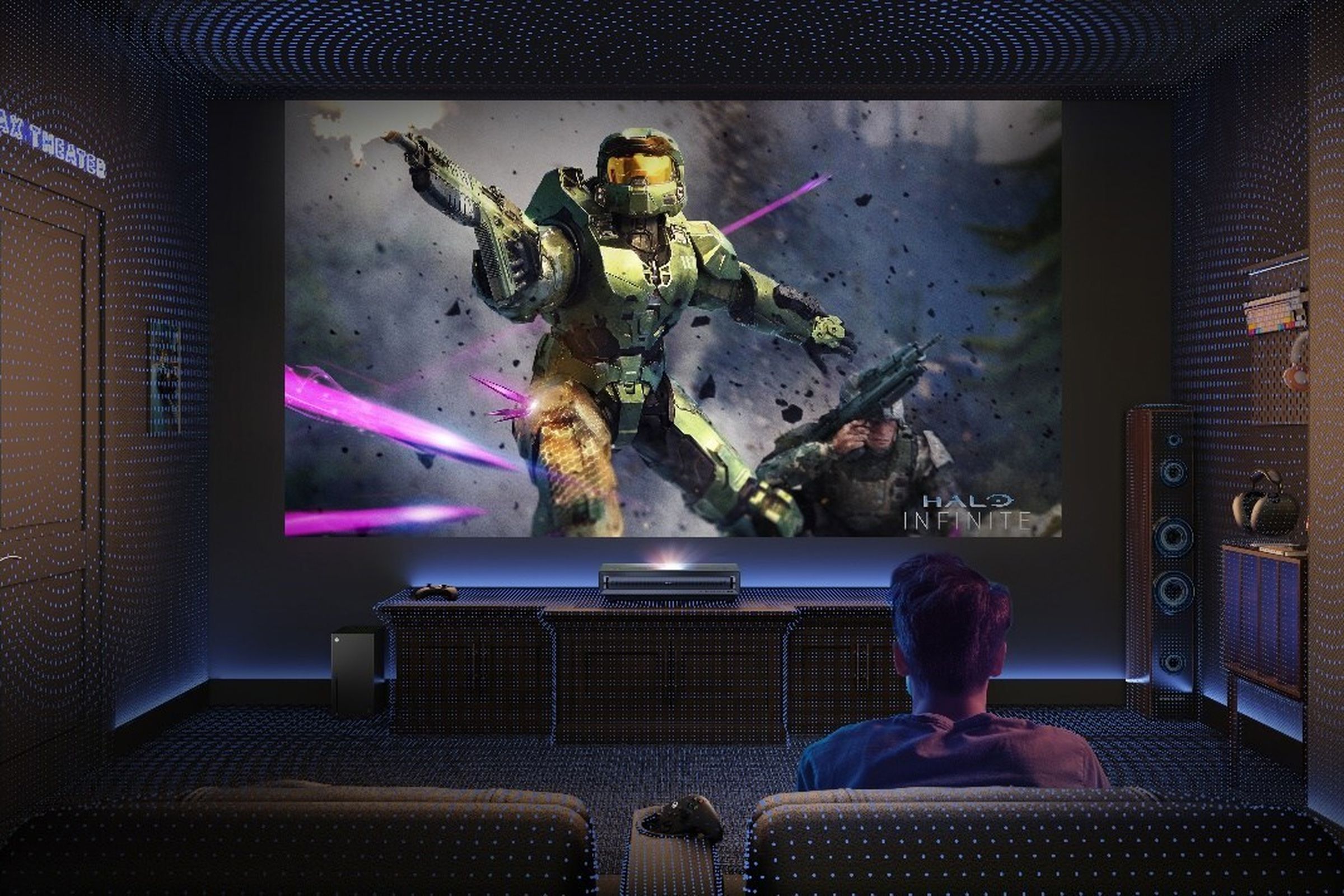 A gamer playing Halo projected on a large screen using the Hisense PX3-PRO UST laser projector.