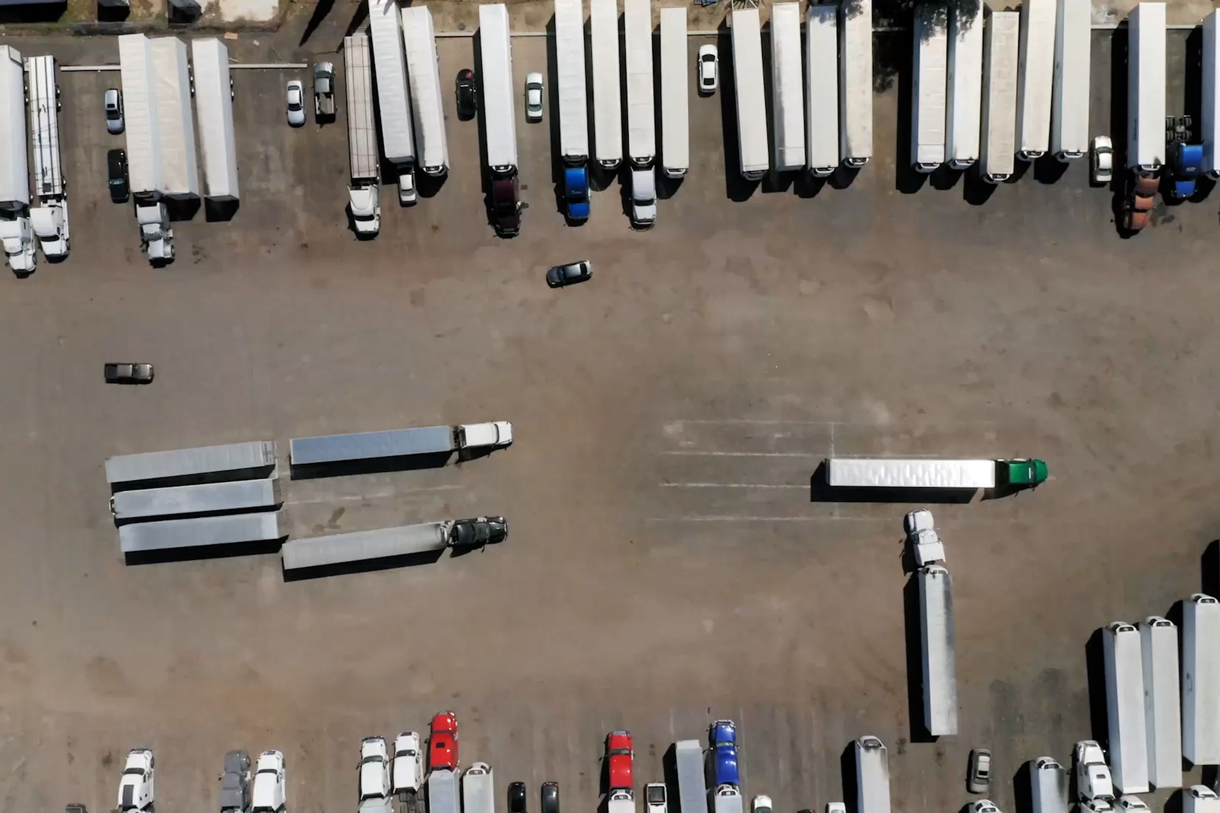 An aerial view of many semi-trailer trucks in a parking lot.