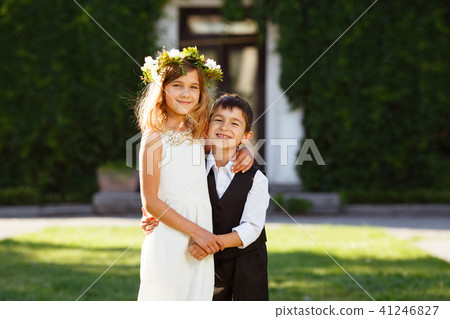 A girl in a white dress hugs a boy 41246827