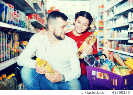 Smiling family couple buying vegetable oil 45290350