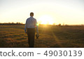 Business man with briefcase goes on beautiful sunset after working day 49030139