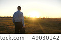 Business man with briefcase goes on beautiful sunset after working day 49030142