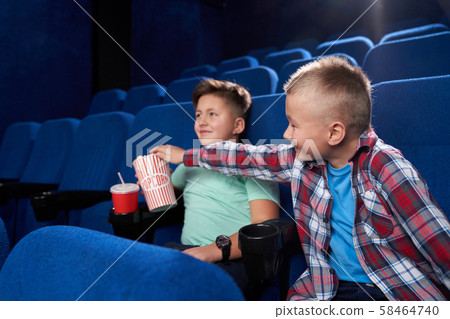 Side view of funny boys watching comical movie together in cinema 58464740