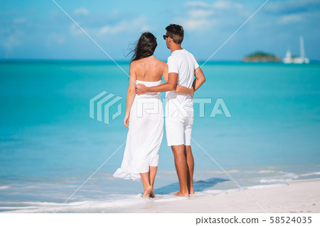 Young couple walking on tropical beach with white sand and turquoise ocean water at Antigua island 58524035