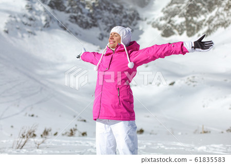 Young woman in pink ski jacket, gloves and pants, 61835583