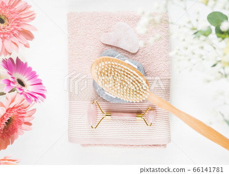 Massage brush, stone, face roller on pink towel 66141781