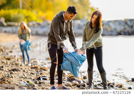 Team of environmental conservation volunteers cleaning beach on sunny day 67225126