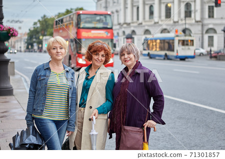 Cheerful beautiful middle-aged women walk in city center at summer. 71301857