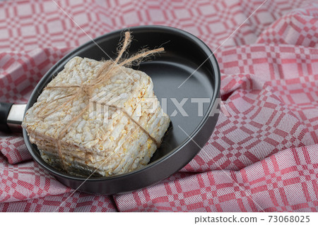 A black pan full of puffed rice bread on a tablecloth 73068025