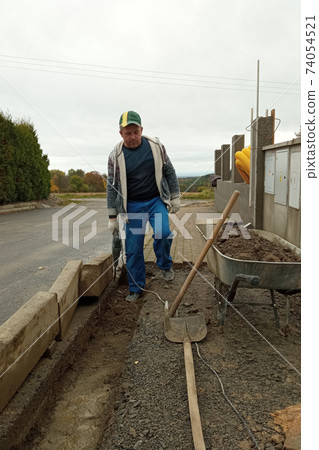 The master lays paving stones for the sidewalk and yard path. 74054521