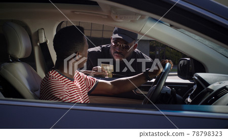 Black policeman checking documents of driver 78798323