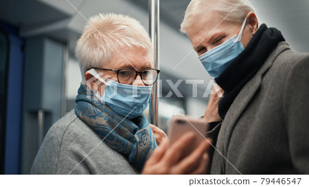 two female tourists communicating via video link during a subway ride. 79446547