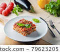 Piece of lasagna on white plate with knife and 79623205