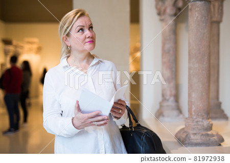 Mature woman visitor holding guidebook 81972938