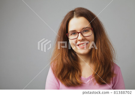 Girl with glasses smiles. Young redhead woman portrait on a solid white background 81388702