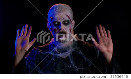 Sinister man Halloween crazy zombie with bloody wounded scars face scared by police lights surrender 82536446