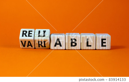 Variable or reliable symbol. Turned wooden cubes and changed the word variable to reliable. Beautiful orange background, copy space. Business and variable or reliable concept. 83914133