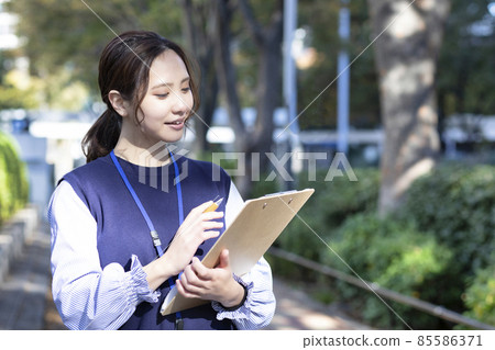 Photo material of a woman taking a survey on a street corner 85586371