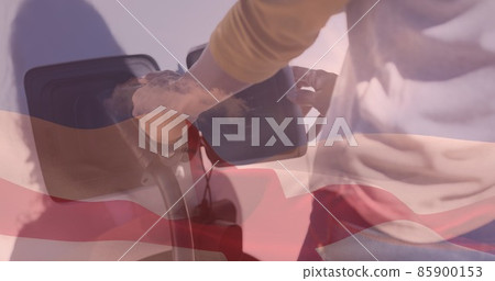 Double exposure of man plugging in charger to electric vehicle at station and english flag 85900153