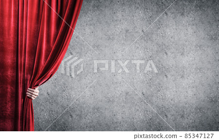 Concrete wall behind drapery curtain and hand opening it 85347127