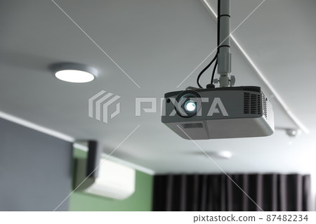 Modern video projector on ceiling in room 87482234