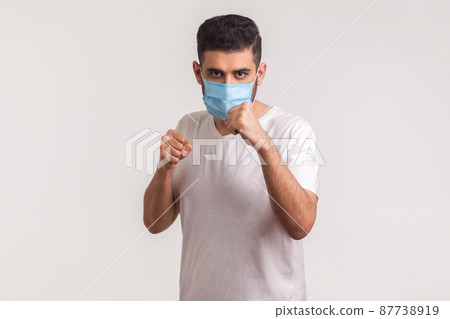 Man in surgical mask punching boxing to camera, fighting against contagious disease, coronavirus infection, respiratory illness such as flu, 2019-nCoV, ebola. studio shot isolated on white background 87738919