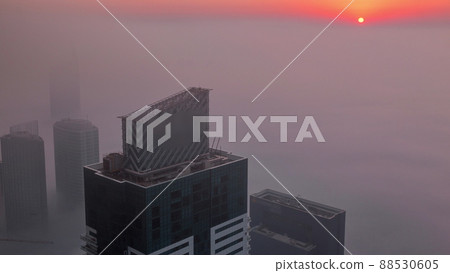 Rare early morning winter fog above the Dubai Marina skyline and skyscrapers lighted by sun aerial timelapse. 88530605