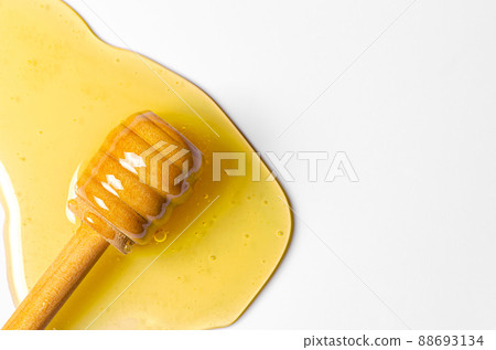 Spilled fresh honey with a wooden spoon. White background. Copy space 88693134