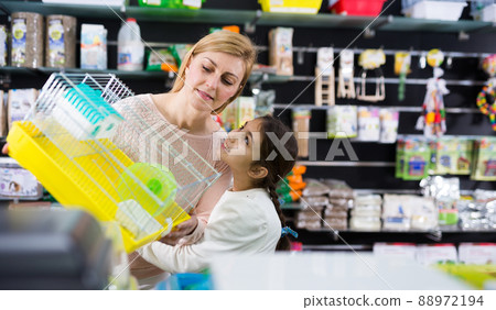 Smiling woman with her daughter choosing hamster cage 88972194