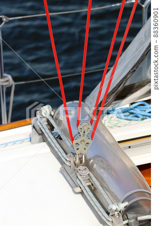 A photo of the contrast between a white yacht berthing at the marina and a red rope under clear skies. 88360901