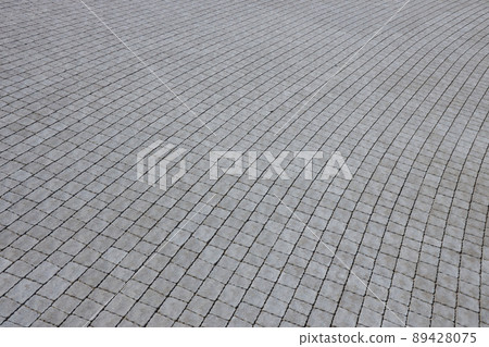 Gray color paving slabs in the pedestrian street sidewalk. Rough cobblestone pattern with many square shaped stones 89428075