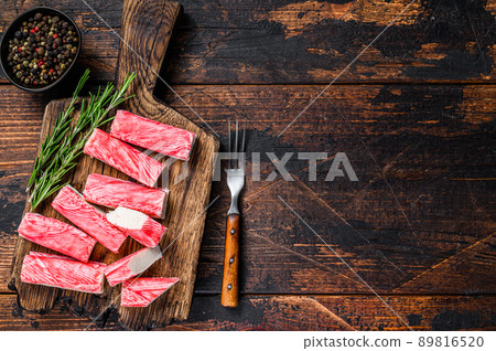 Sliced Crab surimi sticks on a wooden cutting board. Dark wooden background. Top view. Copy space 89816520