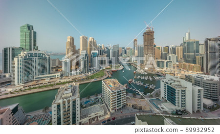 Dubai Marina with several boat and yachts parked in harbor and skyscrapers around canal aerial timelapse. 89932952