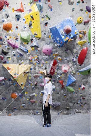 Bouldering image Elementary school student in a mask standing in front of the wall 91559304