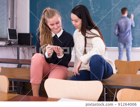 Girls students using smartphone during break in auditorium 91264006