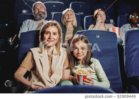 Portrait of modern Caucasian woman and her preteen daughter sitting at cinema looking at camera 92909449