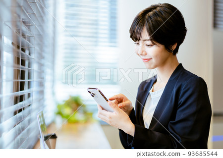 A woman operating a smartphone in the office 93685544